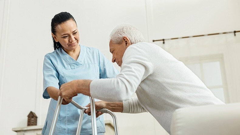 Nurse helping older man with a walker 