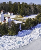 Icy shoreline of Door County Wisconsin with lighthouse, aerial view.