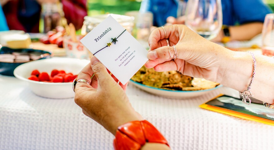 Close-up of women holding friendship bracelet during a picnic in the park