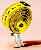 A man hunched over with a extremely large tape measure on his back