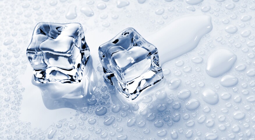Two ice cubes on a light surface with surrounding droplets of water