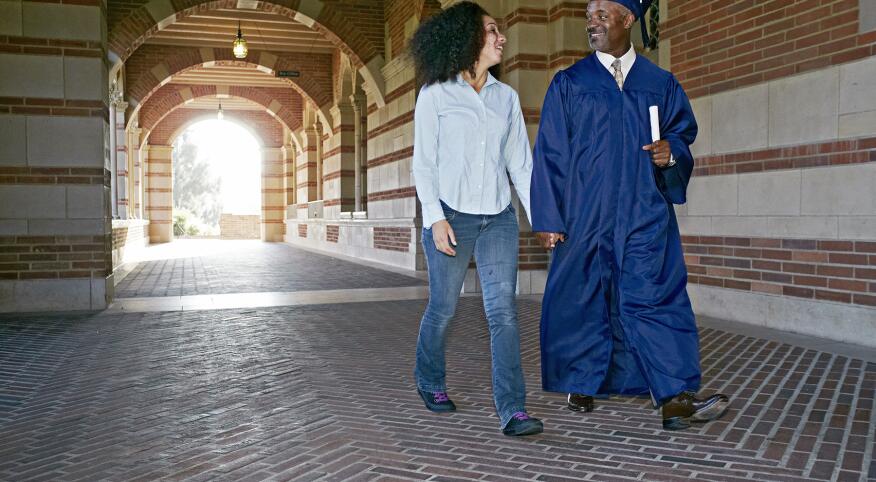 Daughter walking with father in graduation cap and gown