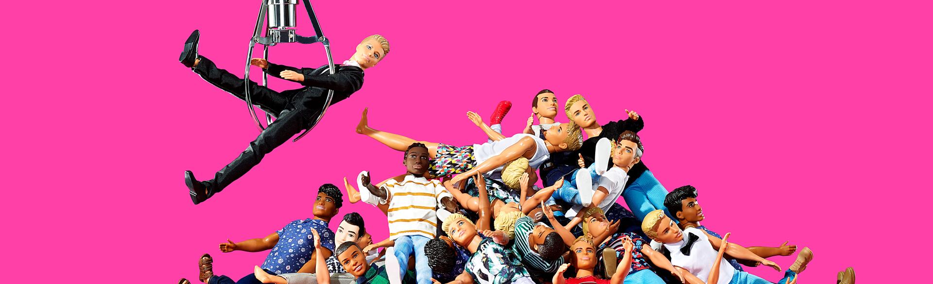 A pile of ken dolls with one ken doll being pulled from the pile by an arcade game claw.