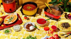 Overhead shot of crockpot meals and garnishes on yellow tablecloth