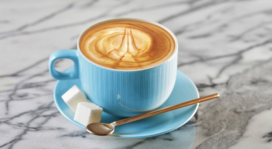 Latte with foam art in the shape of prayer hands