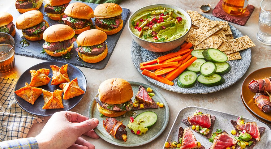 Hand grabbing plate of food from party spread