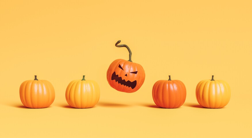 Row of pumpkins with one with angry face on orange background.