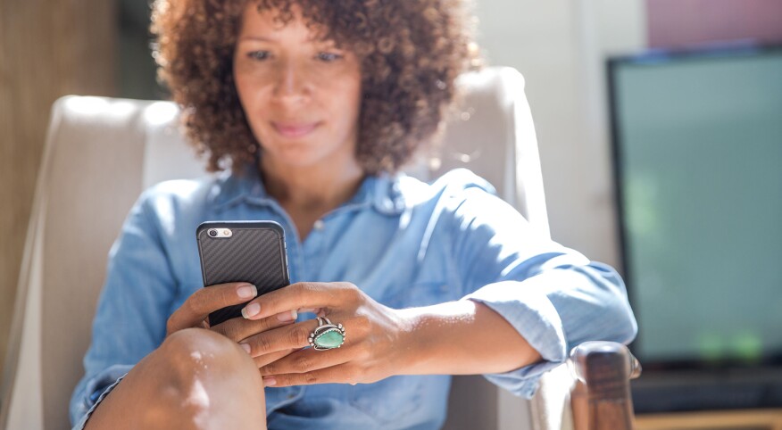 Woman Relaxing At Home While Reading On Her Smartphone