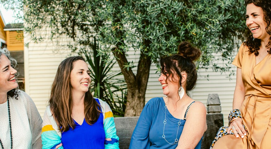 Group of friends sitting on a bench and laughing together