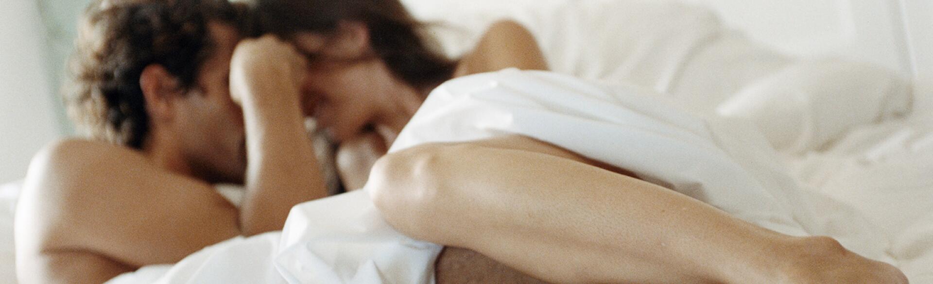 man and women in bed under the sheets getting intimate