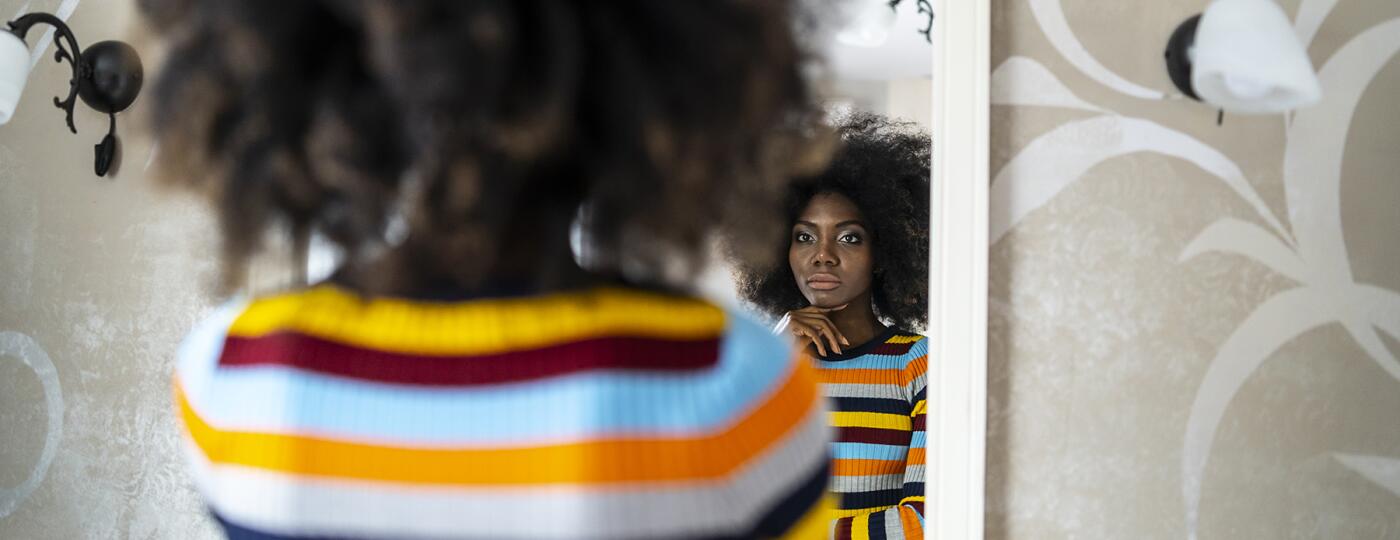 image_of_woman_looking_in_mirror_contemplative_GettyImages-1135286715_1800