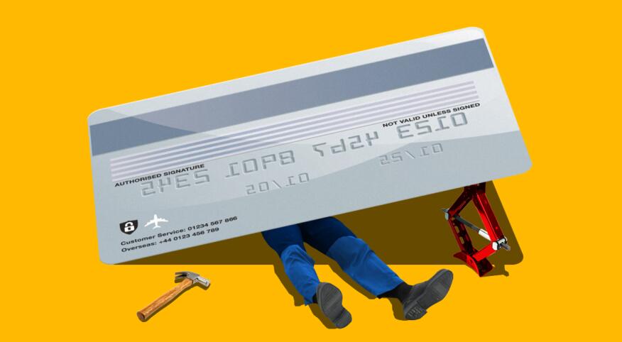 Photo composite of a man under a credit card with tools looking like a mechanic trying to fix it.