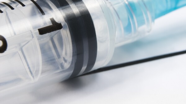 Close-up of flu shot syringe with word 'flu'