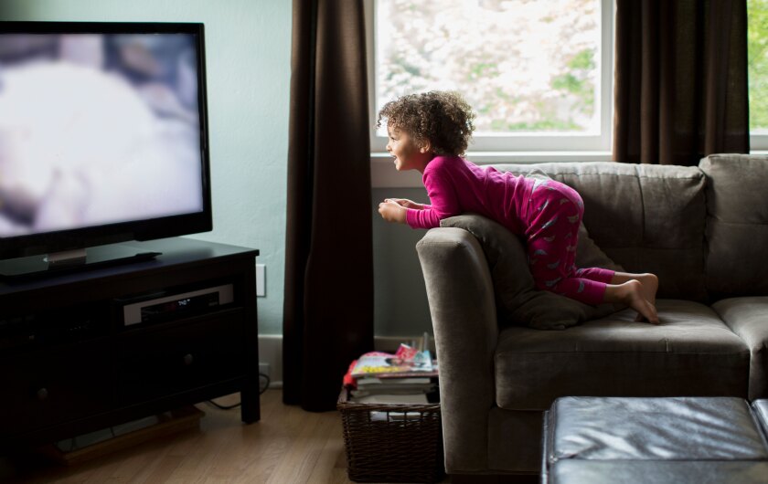 Let-go-of-perfection-little-girl-watching-tv-from-sofa-smiling-GettyImages-155770683.jpg