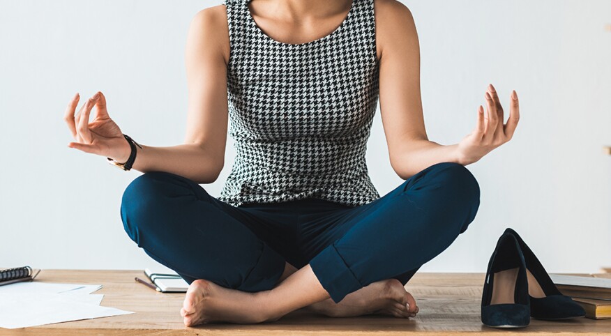 imge_of_black_woman_sitting_cross_legged_on_office_desk_GettyImages-949851136_crop_1540