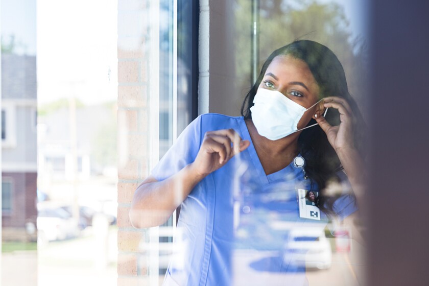 woman_wearing_mask_working_as_nurse_GettyImages-1254704714