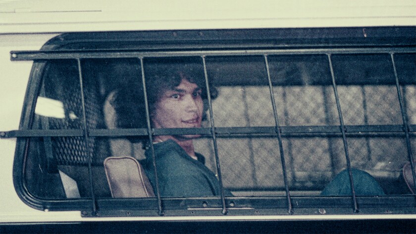 Richard Ramirez, a nocturnal serial killer, sits behind bars inside a police vehicle.