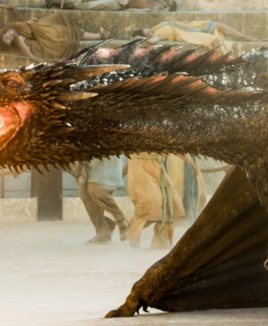 game of thrones character Daenerys Targaryen standing next to a fire breathing dragon