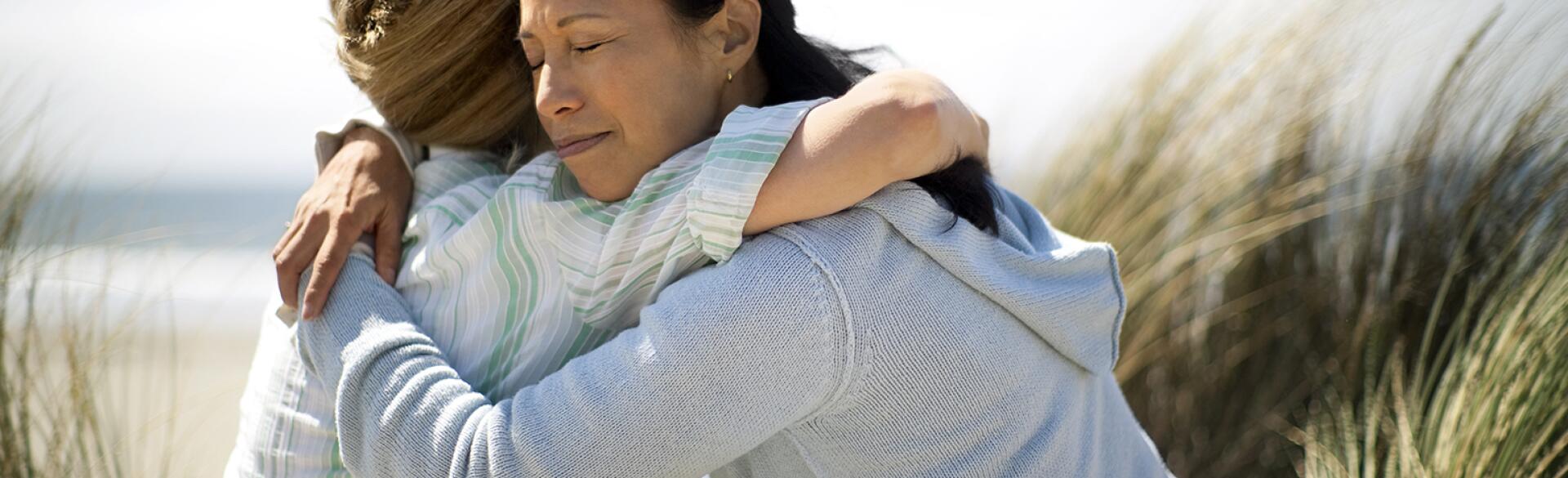 Friends hugging to mourn the loss of one of their parents.
