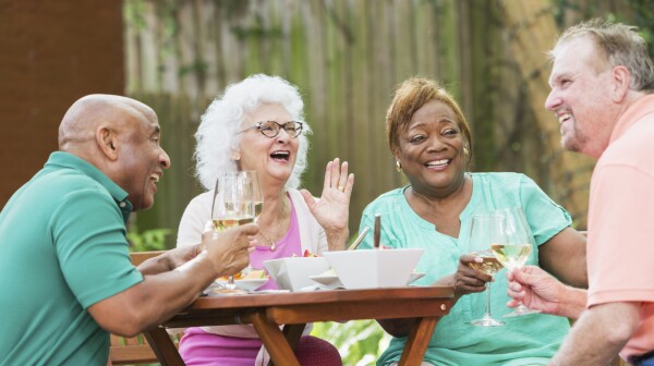 Group of seniors enjoying wine and food in back yard