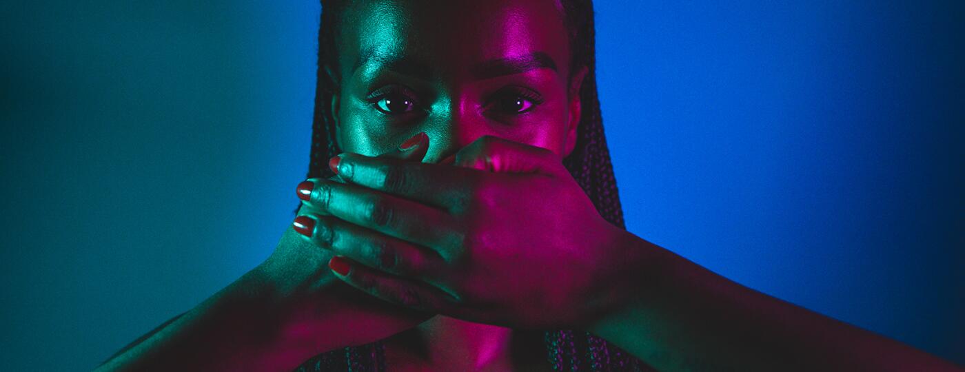image_of_woman_with_hands_covering_mouth_in_studio_with_blue_lights_GettyImages-1255042836_1800