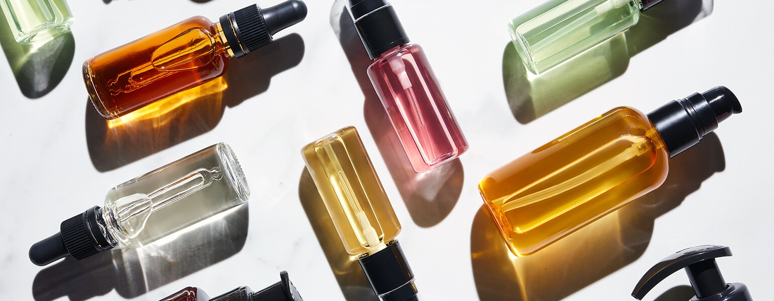 Different Bottles Of Colorful Liquids On White.