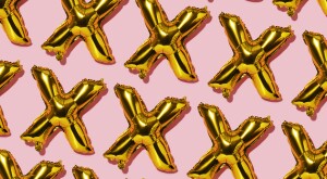 X shaped gold balloons on a pink background to signify lust