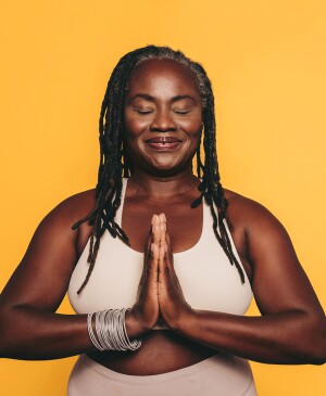 Woman with prayer hands against yellow background