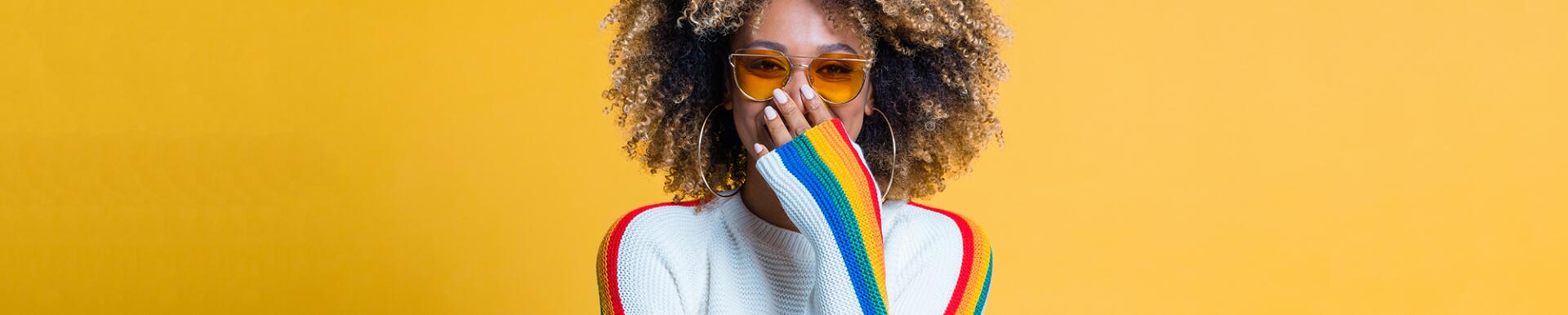 Surprised afro girl standing against yellow background showing her beautiful curls