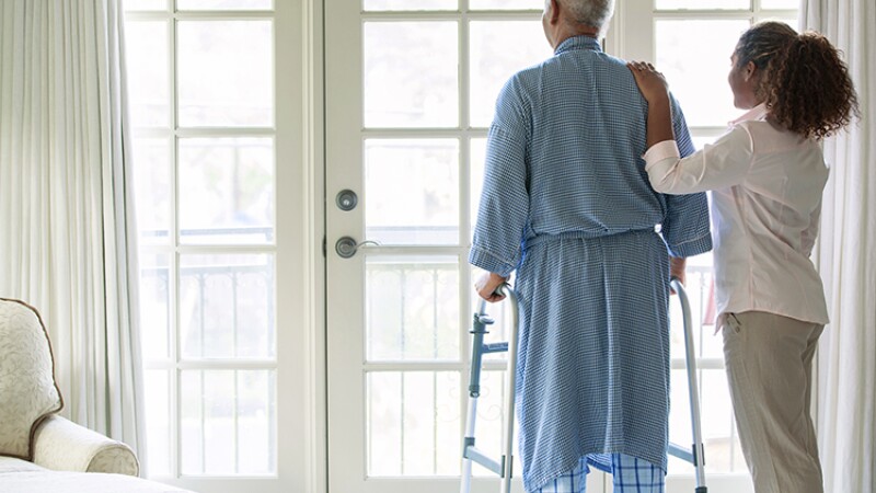 African American woman helping Senior man use walker