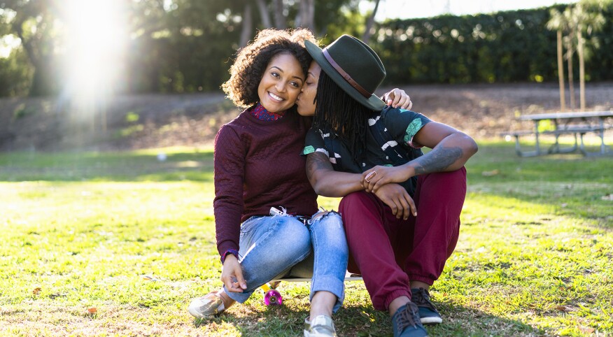 image_of_lesbian_couple_sitting_outside_on_grass_GettyImages-639554785_1800