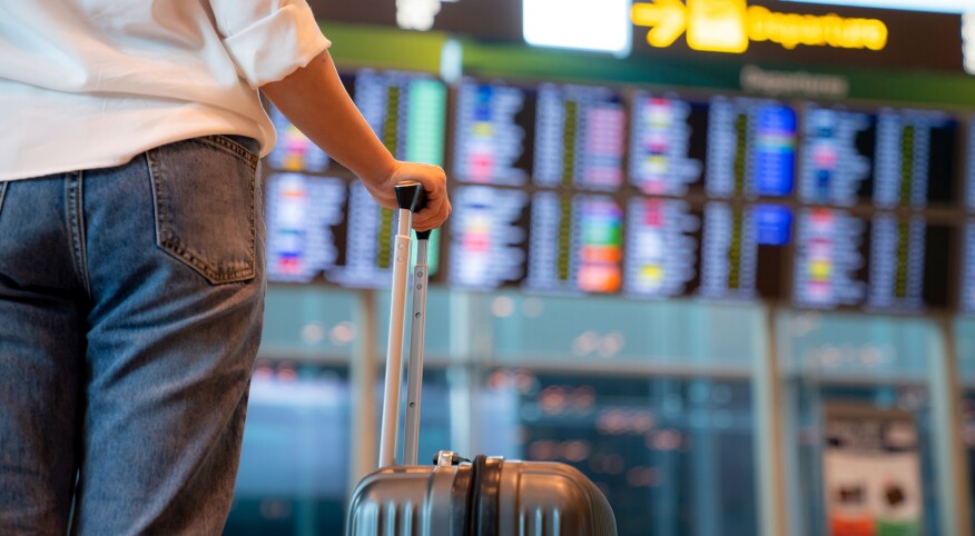 Female traveller standing in front of Flight display schedule in the International airport