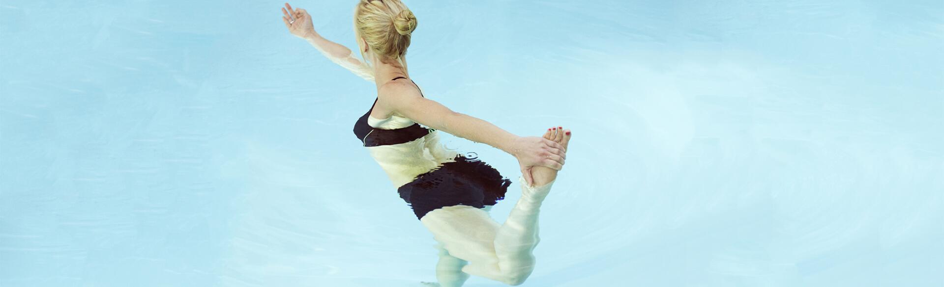 Mid adult woman holding her foot while practicing yoga in a swimming pool