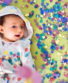 Happy baby girl surrounded by confetti