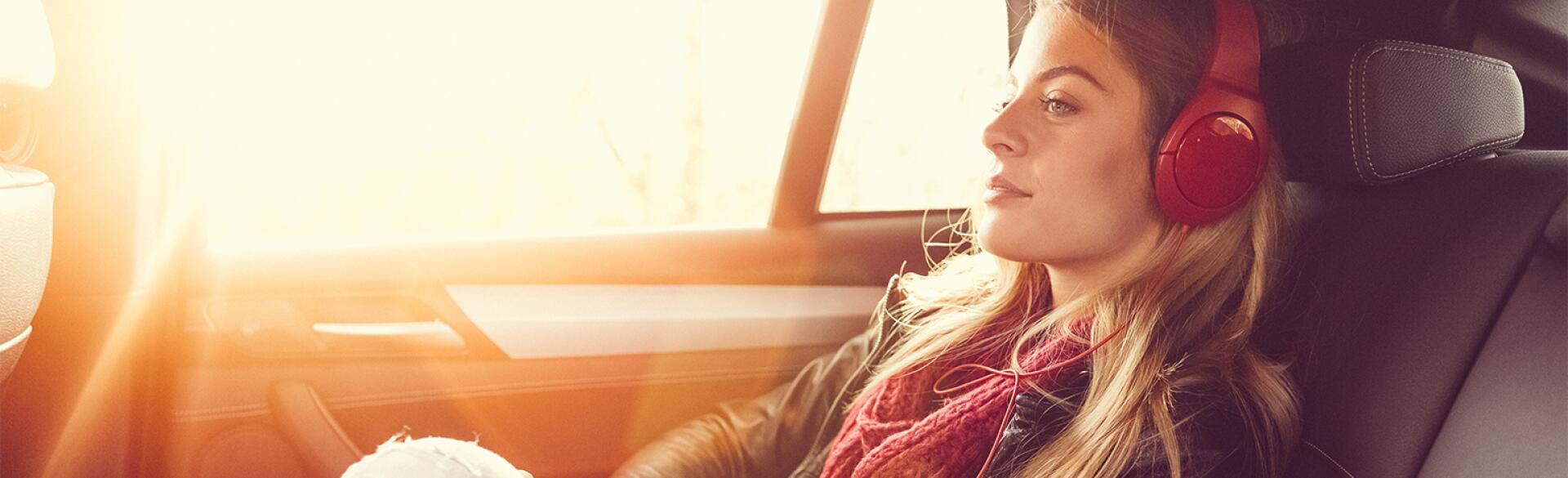 Woman sitting in the back seat of an Uber with headphones on