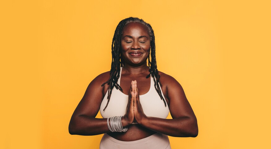 Woman with prayer hands against yellow background