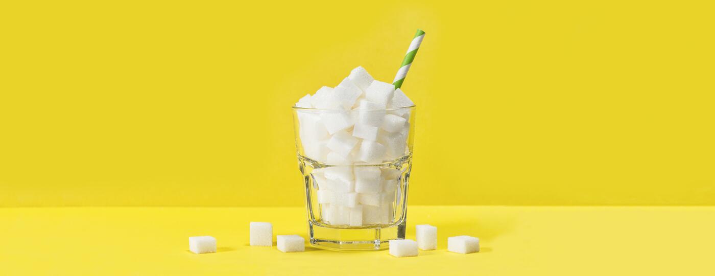 cup filled with sugar cubes with straw in it