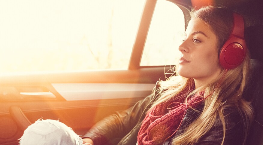 Woman sitting in the back seat of an Uber with headphones on