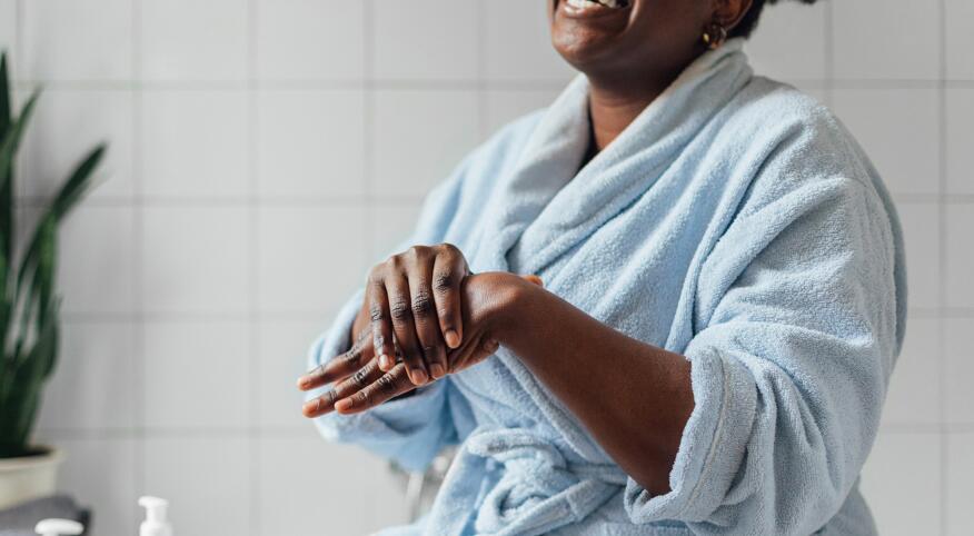 Woman in blue robe applying hand cream in the bathroom