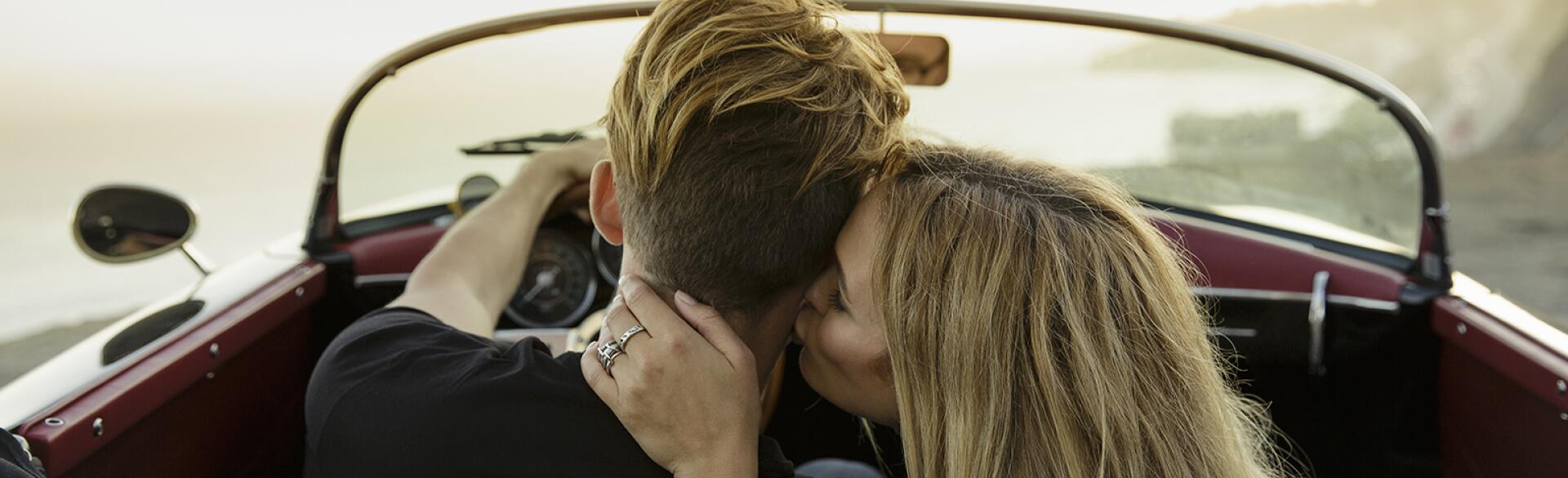 A woman kissing her partner's neck while in a car.