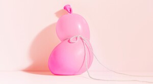A conceptual still-life witha  pink balloon tied off with a string in the middle 