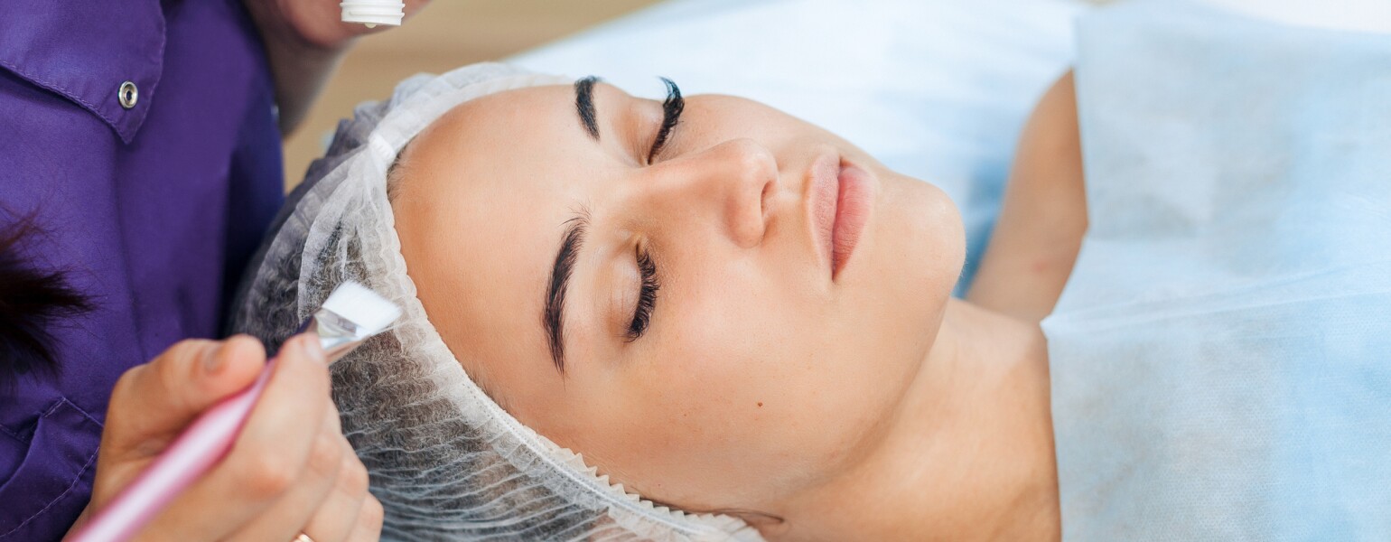 Woman cosmetologist to apply the cream-mask on the face. Cosmetic procedures
