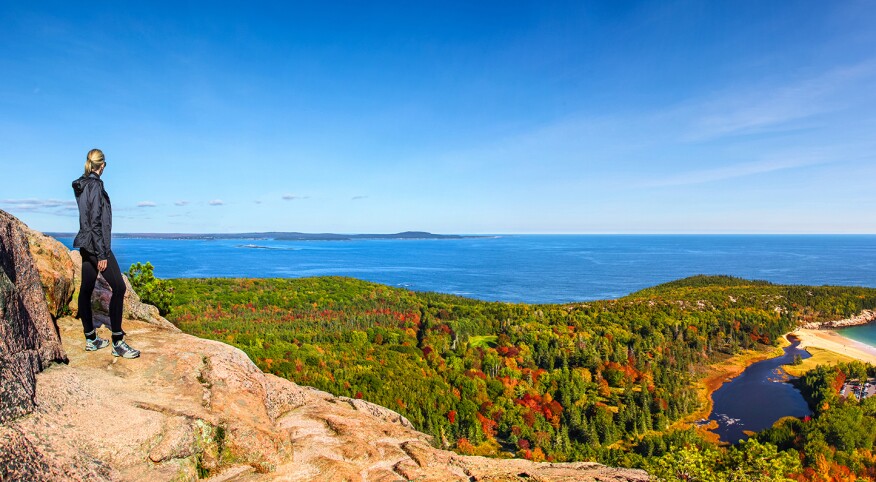 Hiker enjoying the panoramic view from the top of Beehive Trail in Acadia National Park