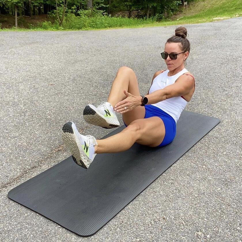 Kendra Jarratt completes ab exercises on a yoga mat outside.