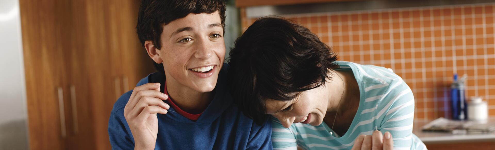 Mother and her teenage son laughing in their kitchen