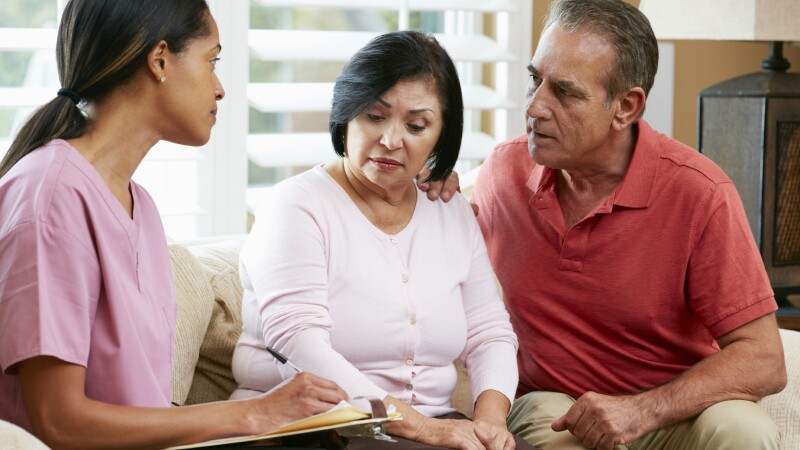 Nurse Making Notes During Home Visit With Senior Couple
