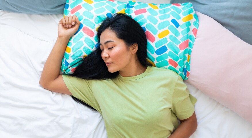 Woman in green t-shirt sleeping in bed