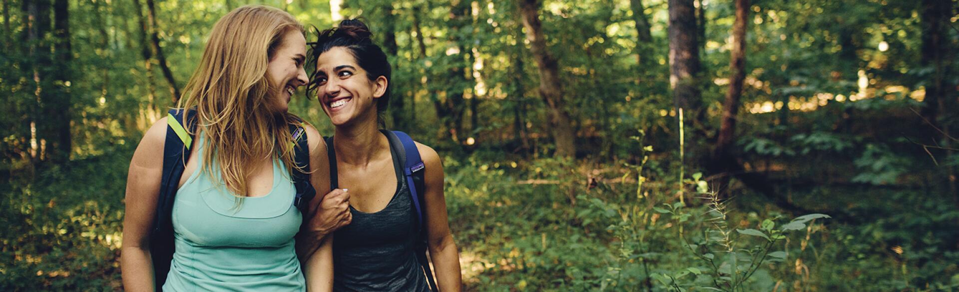 Two women best friends on a hike in the woods.