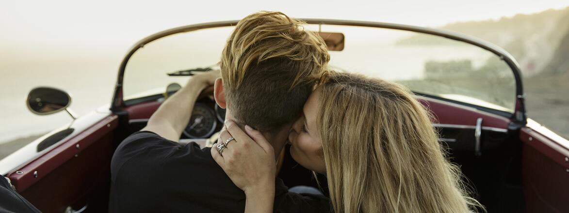 A woman kissing her partner's neck while in a car.