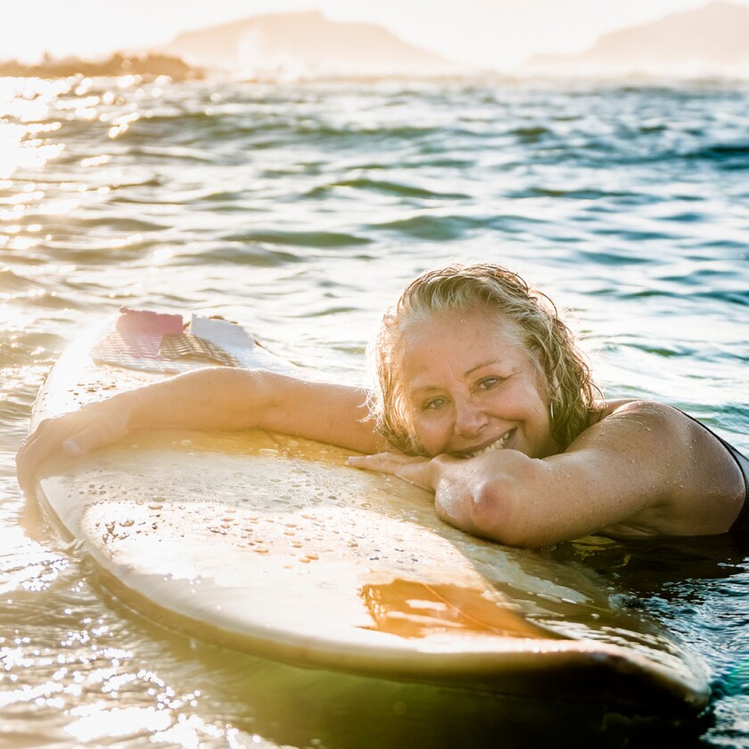 woman in ocean leaning on surfboard